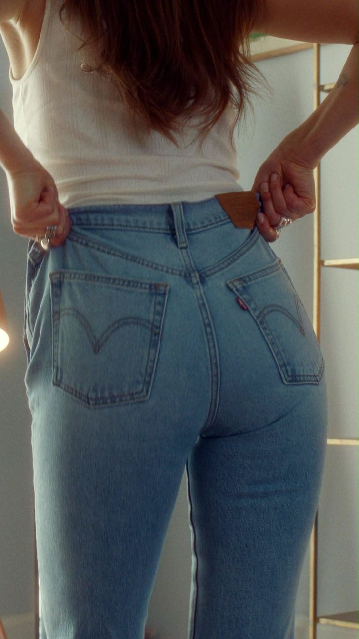 Woman in blue jeans and a white tank top from behind
