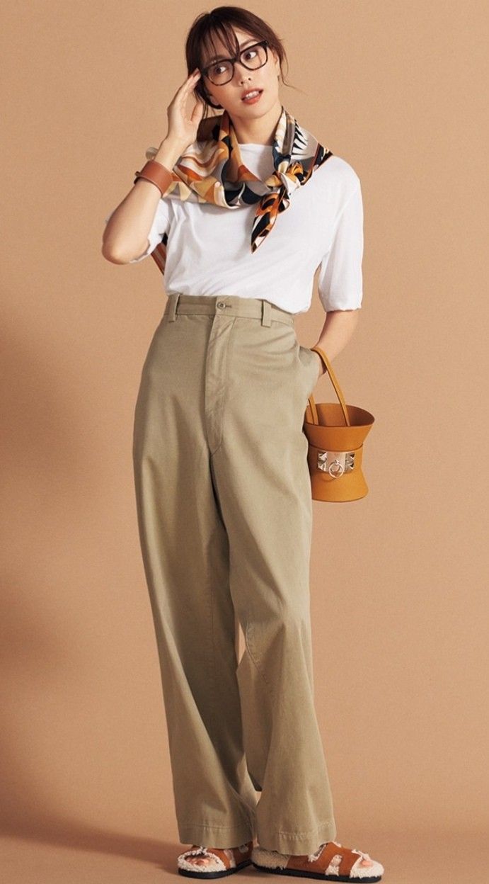 Woman in wide leg pants, white t-shirt, and a silk scarf posing in a studio