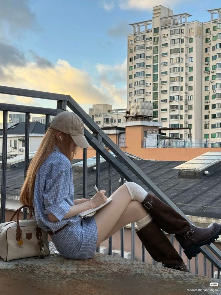 Woman in a plaid shirt and mini skirt writing on a rooftop at golden hour