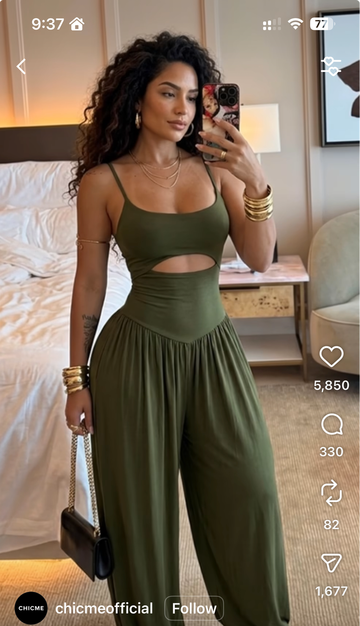 Woman in a green cutout jumpsuit taking a mirror selfie indoors