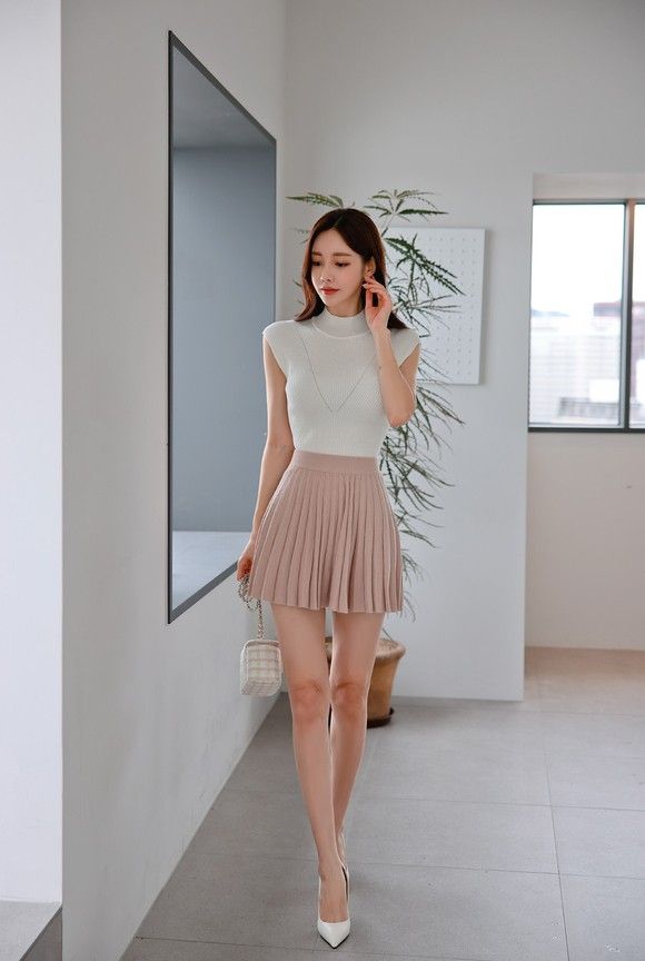 Woman in a white top and pleated mini skirt walking indoors