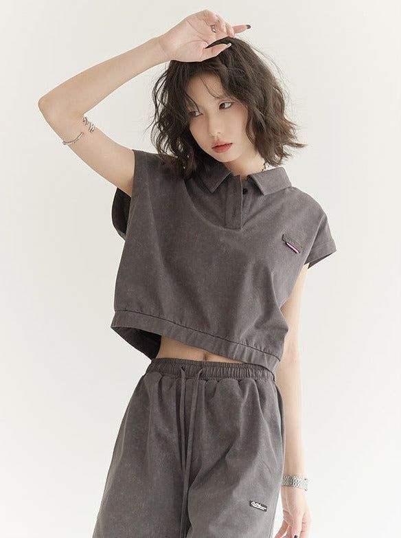 Woman in a dark grey crop top and shorts with one arm raised