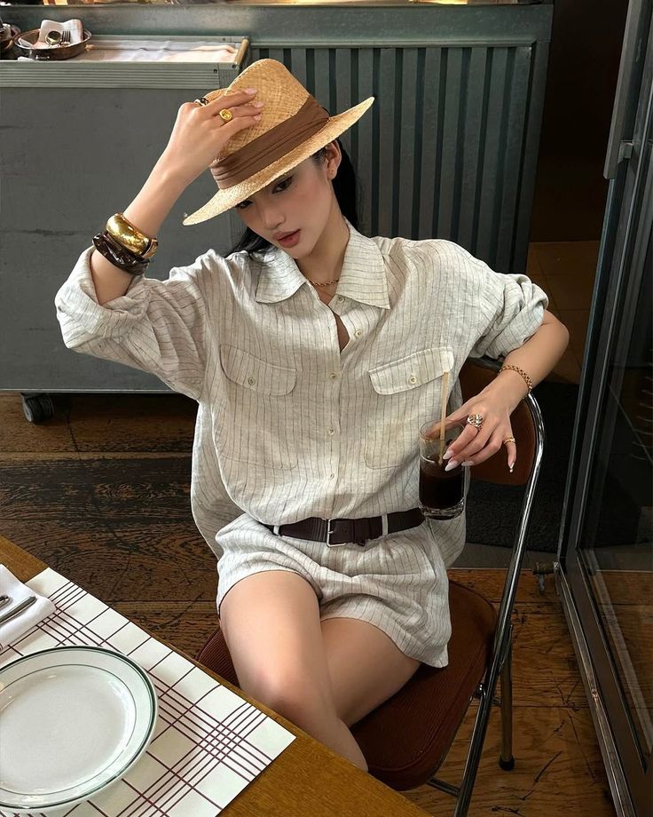 Woman in a straw hat and striped shirt with shorts sitting at a table