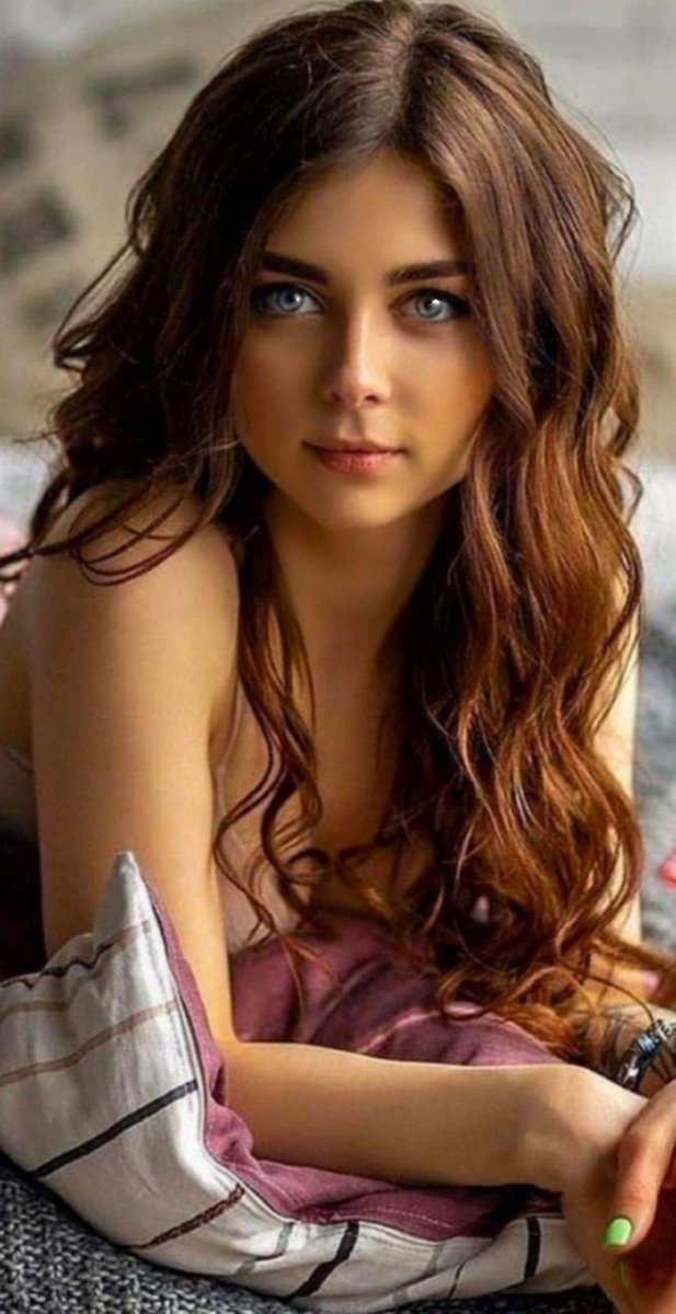 Woman with long wavy hair and blue eyes in an indoor setting