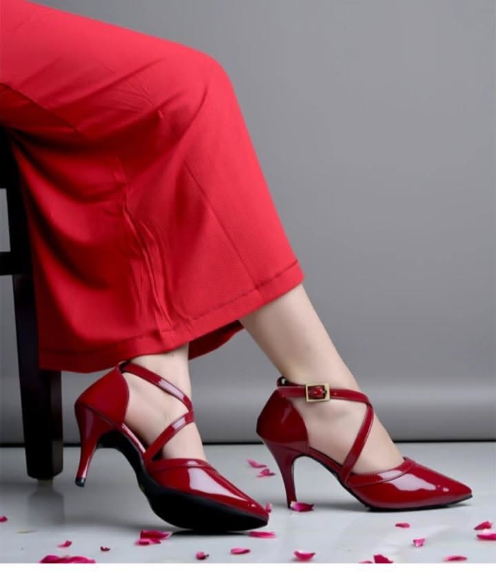 Person wearing red high heels and red pants with scattered rose petals