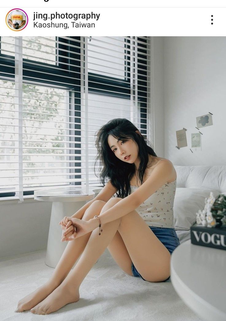 Woman with long dark hair sitting on the floor in a bright room