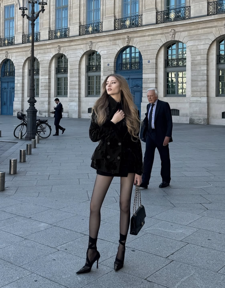 Woman in a black blazer and tights on a city street