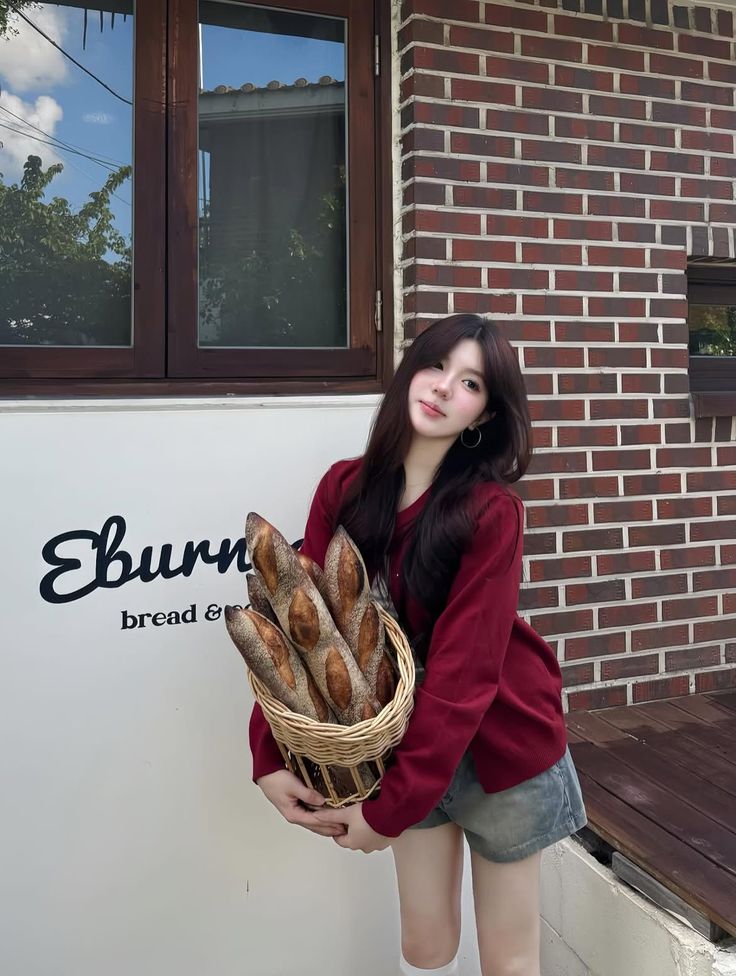 Woman in a red cardigan and denim shorts holding a basket of baguettes
