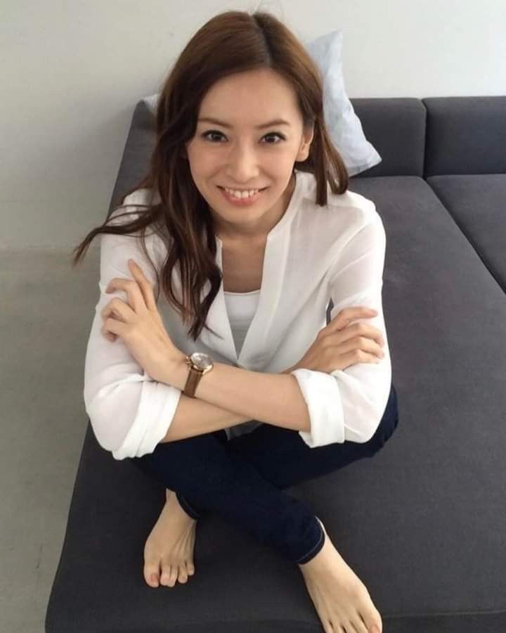 Woman with long hair in a white shirt and jeans sitting on a couch