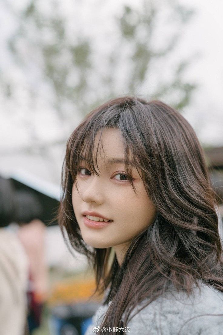 Young woman with long dark hair looking over her shoulder outdoors