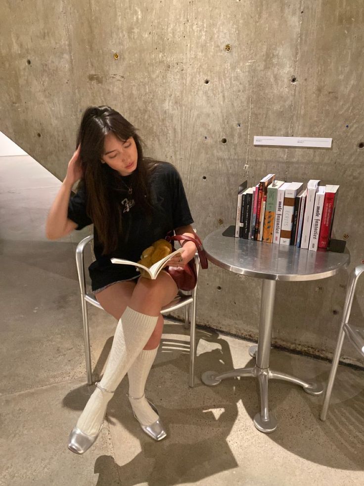 Woman with long hair reading a book while sitting at a table indoors