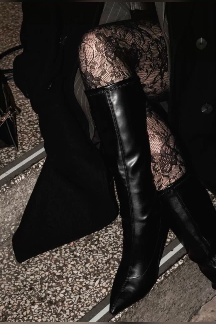 Person wearing black boots and lace stockings with a dark coat