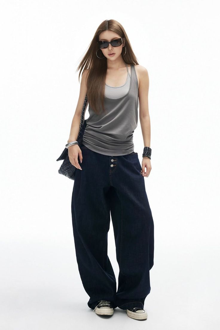 Woman with long hair wearing sunglasses, a tank top, and baggy jeans