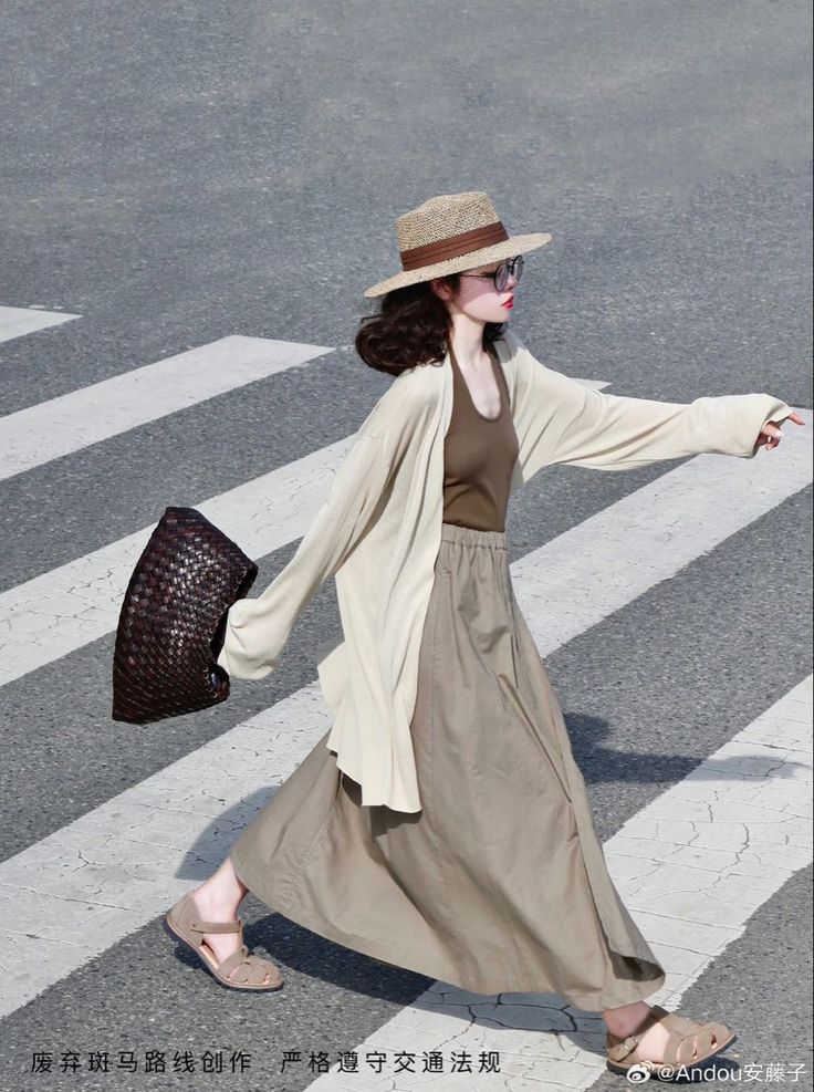 Woman in a straw hat and long skirt crossing a street on a sunny day