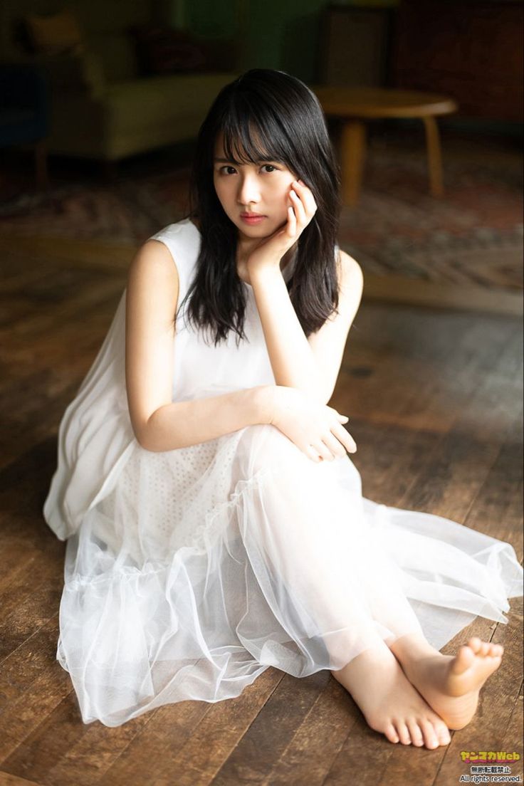 Woman in a white dress sitting on a wooden floor indoors