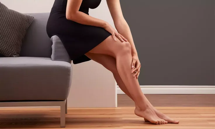 Woman in a black dress sitting on a sofa with bare legs