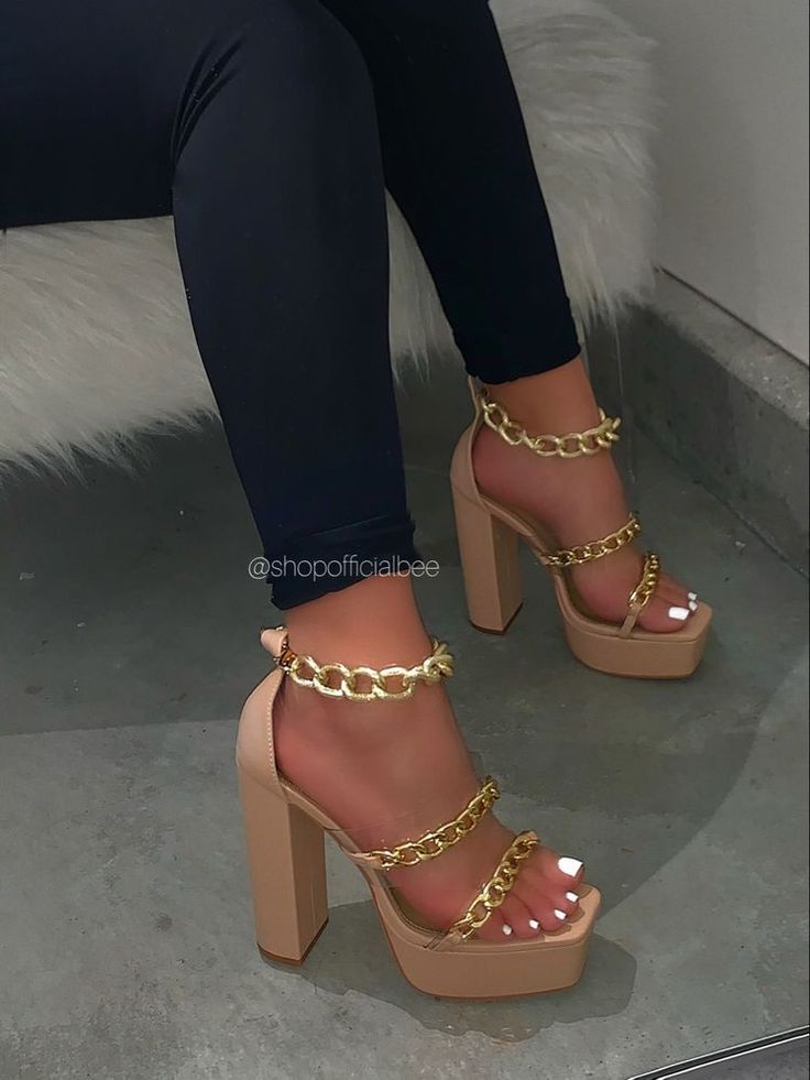 Person wearing nude platform high heels with gold chains and black leggings