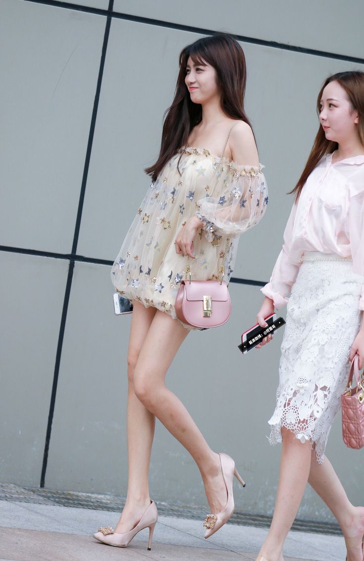 Two women walking on a street, one in an off-shoulder dress