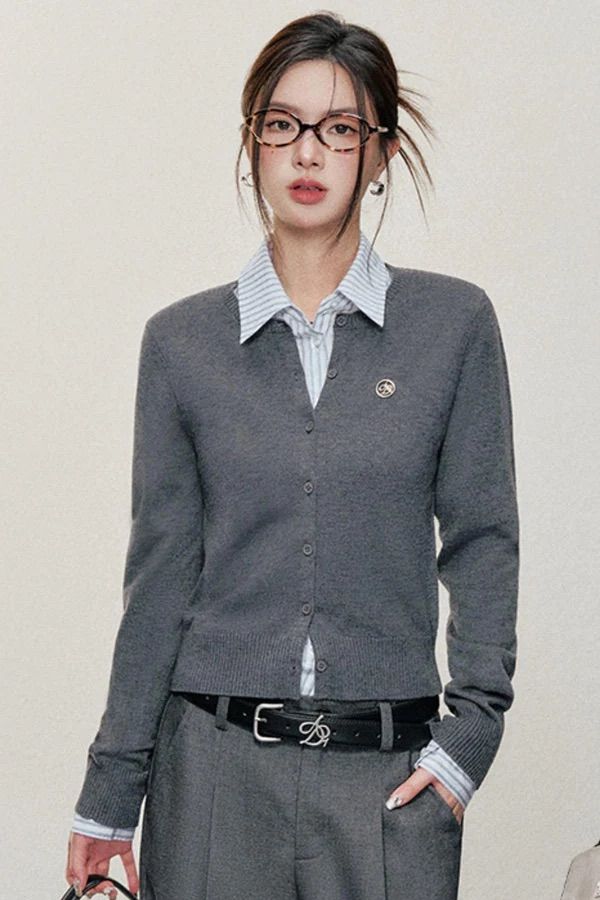 Woman in a gray cardigan, striped shirt, and glasses with hair in an updo