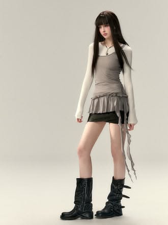 Woman with long black hair wearing a mini skirt and black boots in a studio