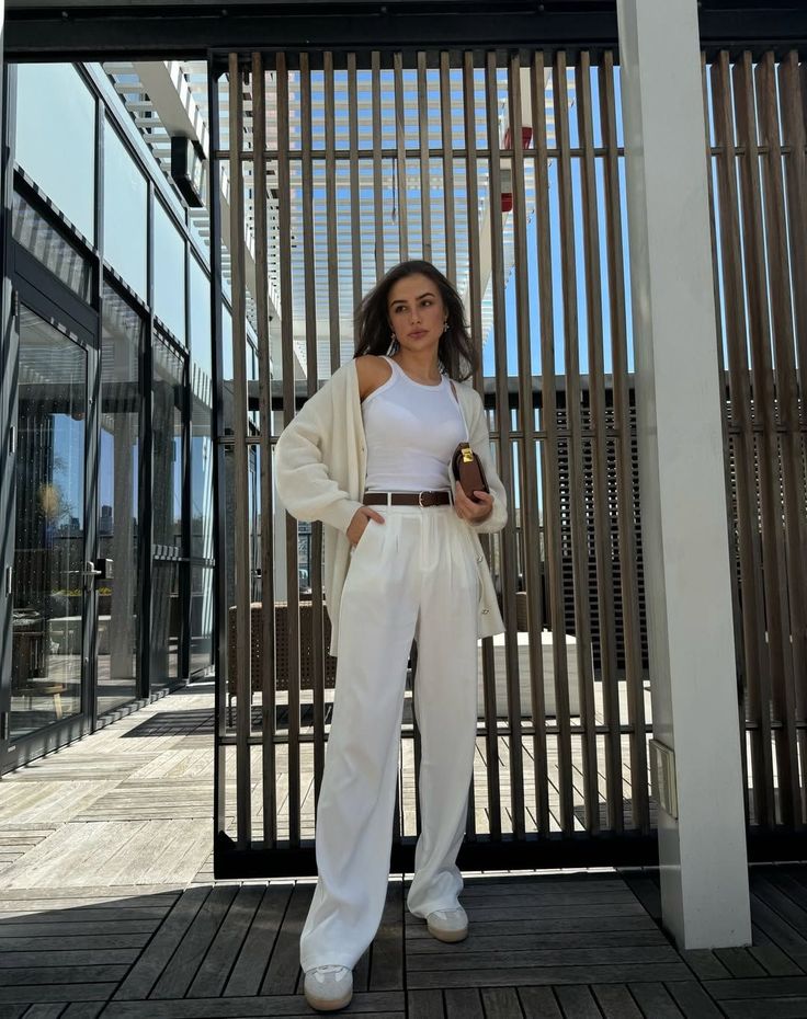Woman in a white outfit with a cardigan and brown accessories outdoors