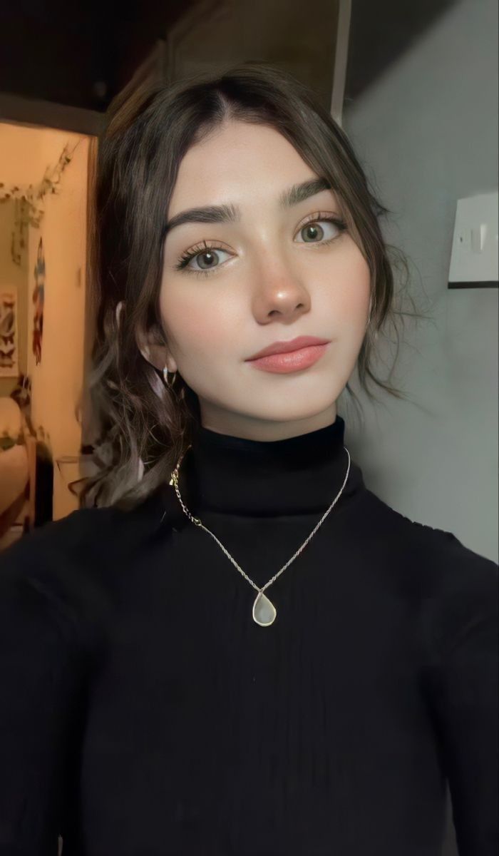 Woman in a black turtleneck with a ponytail and a teardrop necklace