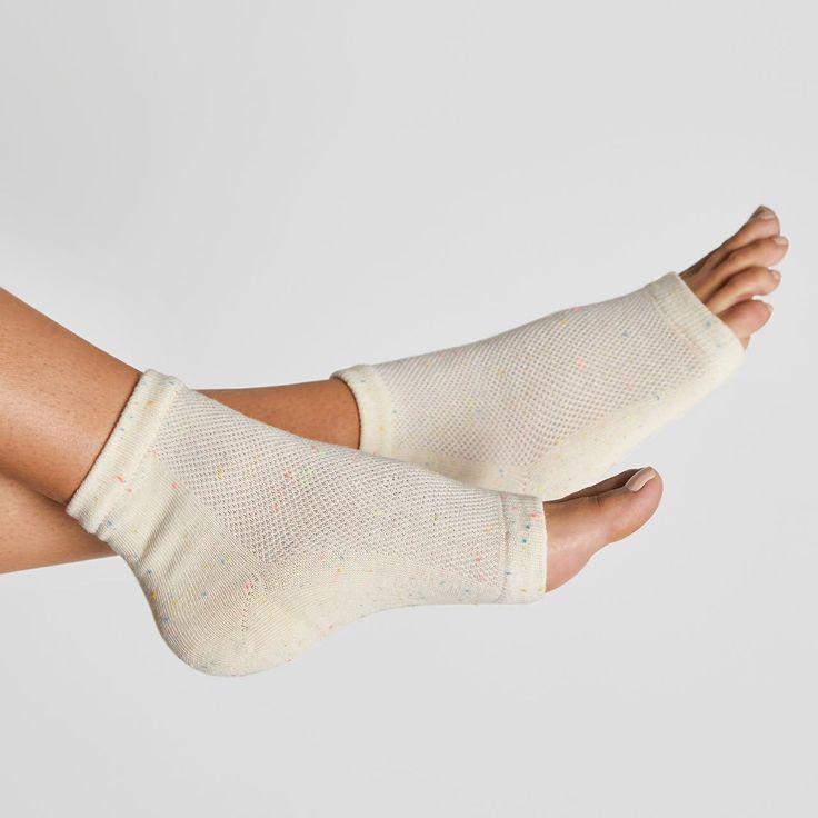 Feet wearing light-colored, open-toed foot sleeves with colorful speckles