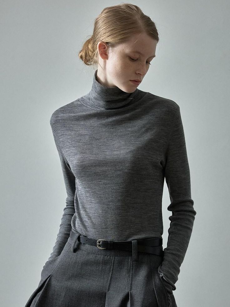 Woman in a grey turtleneck and trousers with her hair in an updo
