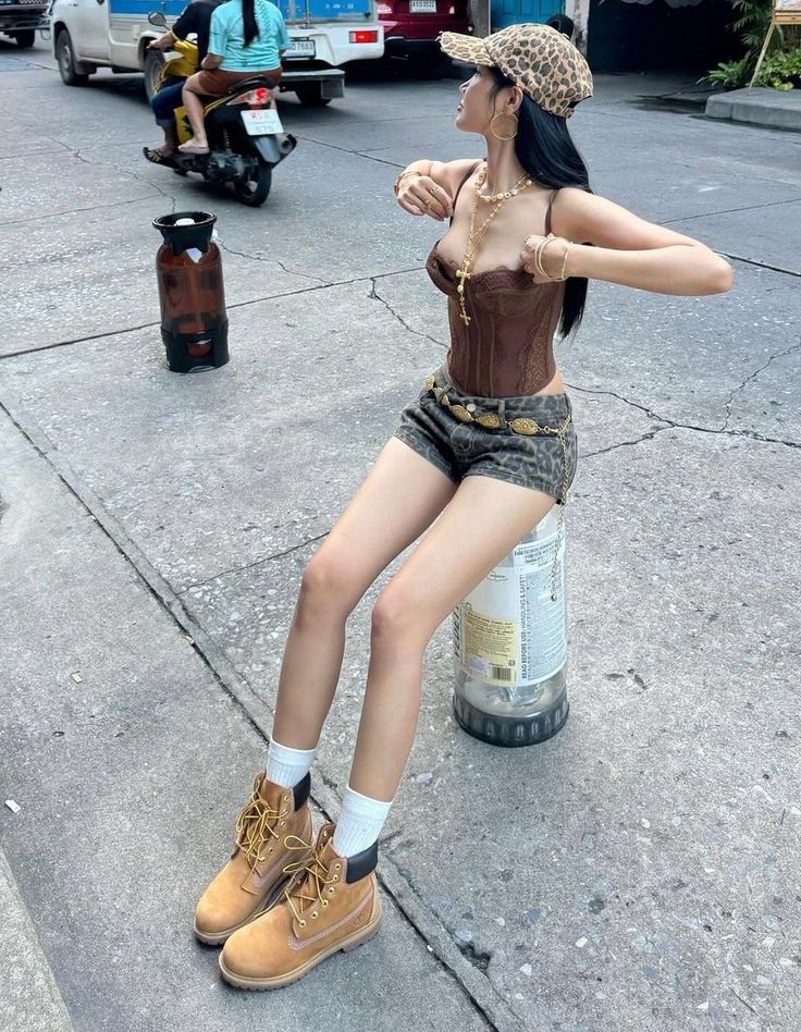 Woman in a brown corset and leopard print shorts sitting on a street