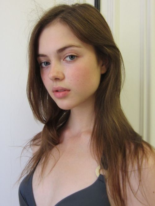Young woman with long brown hair and blue eyes wearing a dark swimsuit