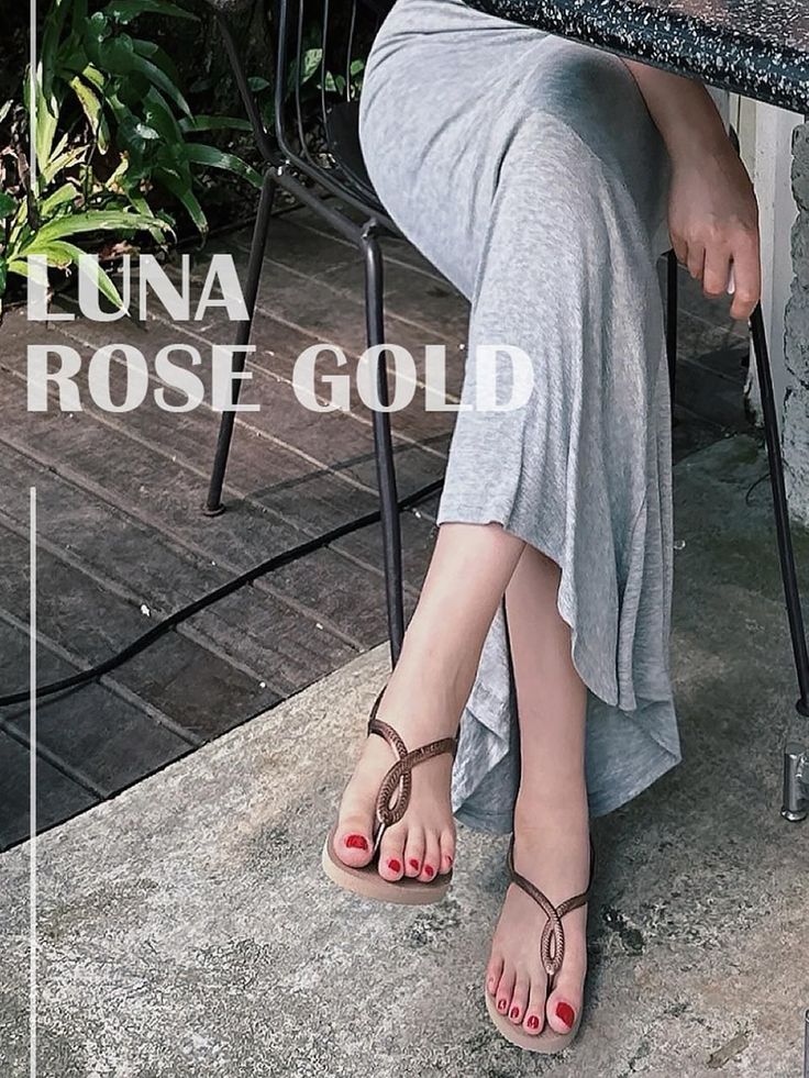 Woman in a long grey dress and sandals with red nail polish, sitting outdoors