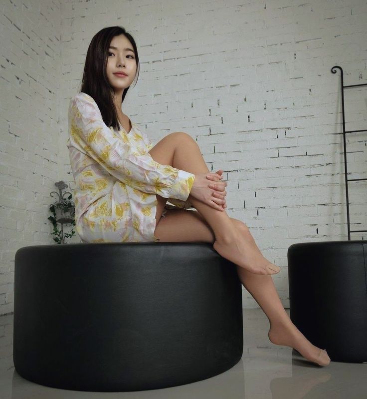 Woman with long hair wearing a floral shirt and sitting on a black stool