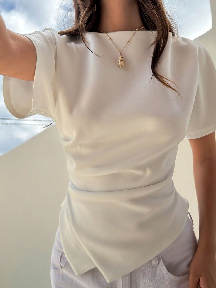 Woman in a white top and gold necklace outdoors during the day