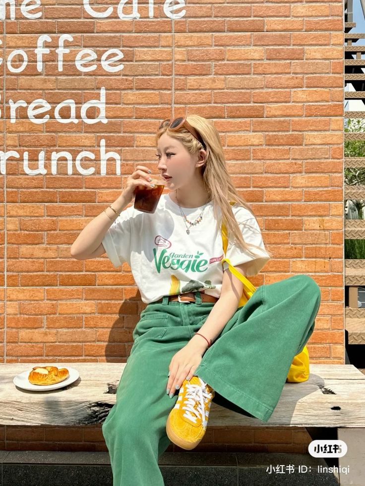 Woman with blonde hair drinking iced coffee outdoors against a brick wall