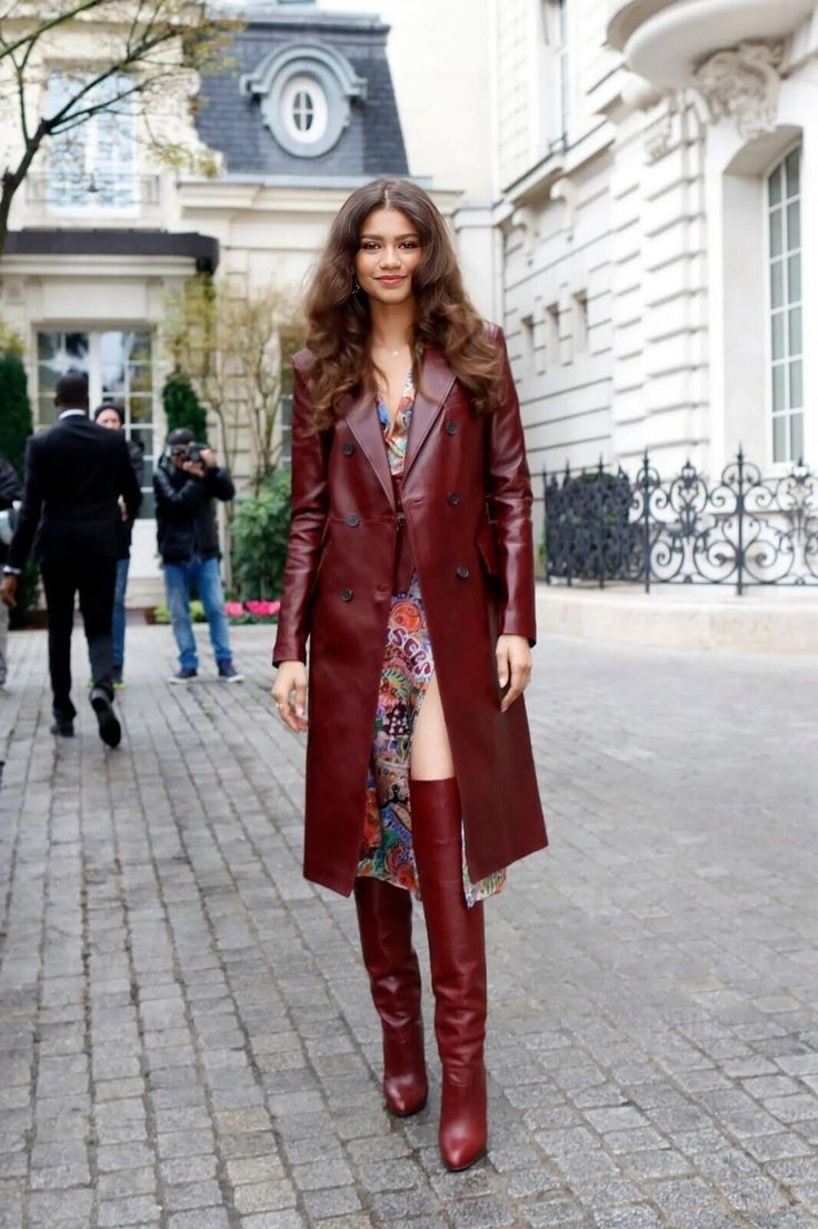 Woman in a red leather coat and boots walking on a cobblestone street