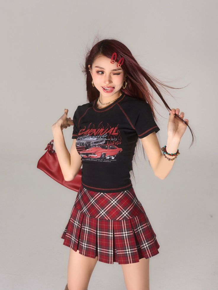 Woman in a black crop top and red plaid skirt winking at the camera