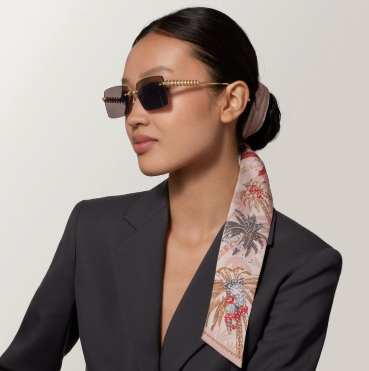 Woman in a black blazer and sunglasses with a patterned silk scarf in her hair