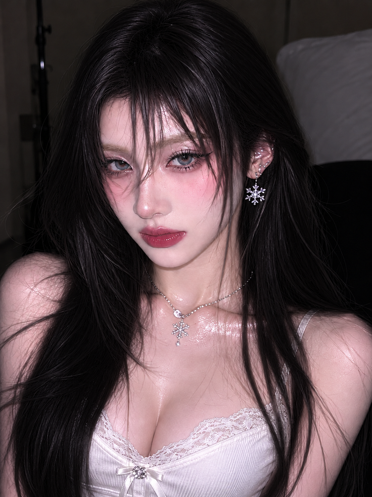 Woman with long dark hair and snowflake jewelry in a white lace-trimmed top
