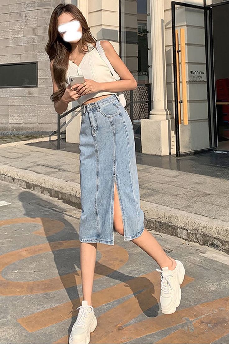 Woman in a denim skirt and white top walking outdoors