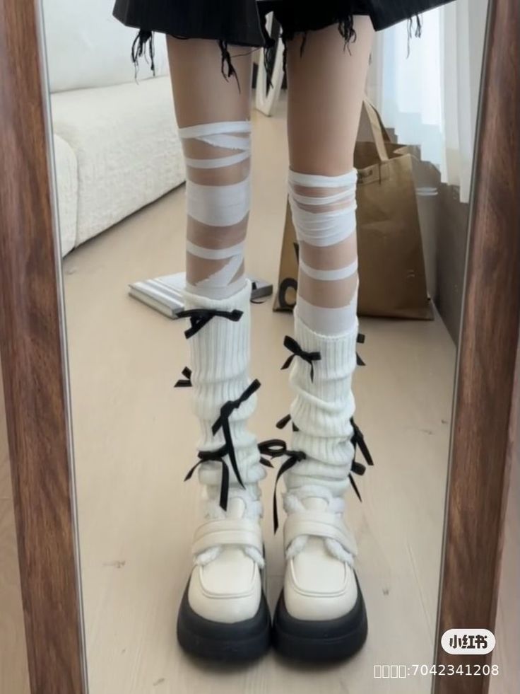 Person wearing white leg warmers with black bows and platform shoes
