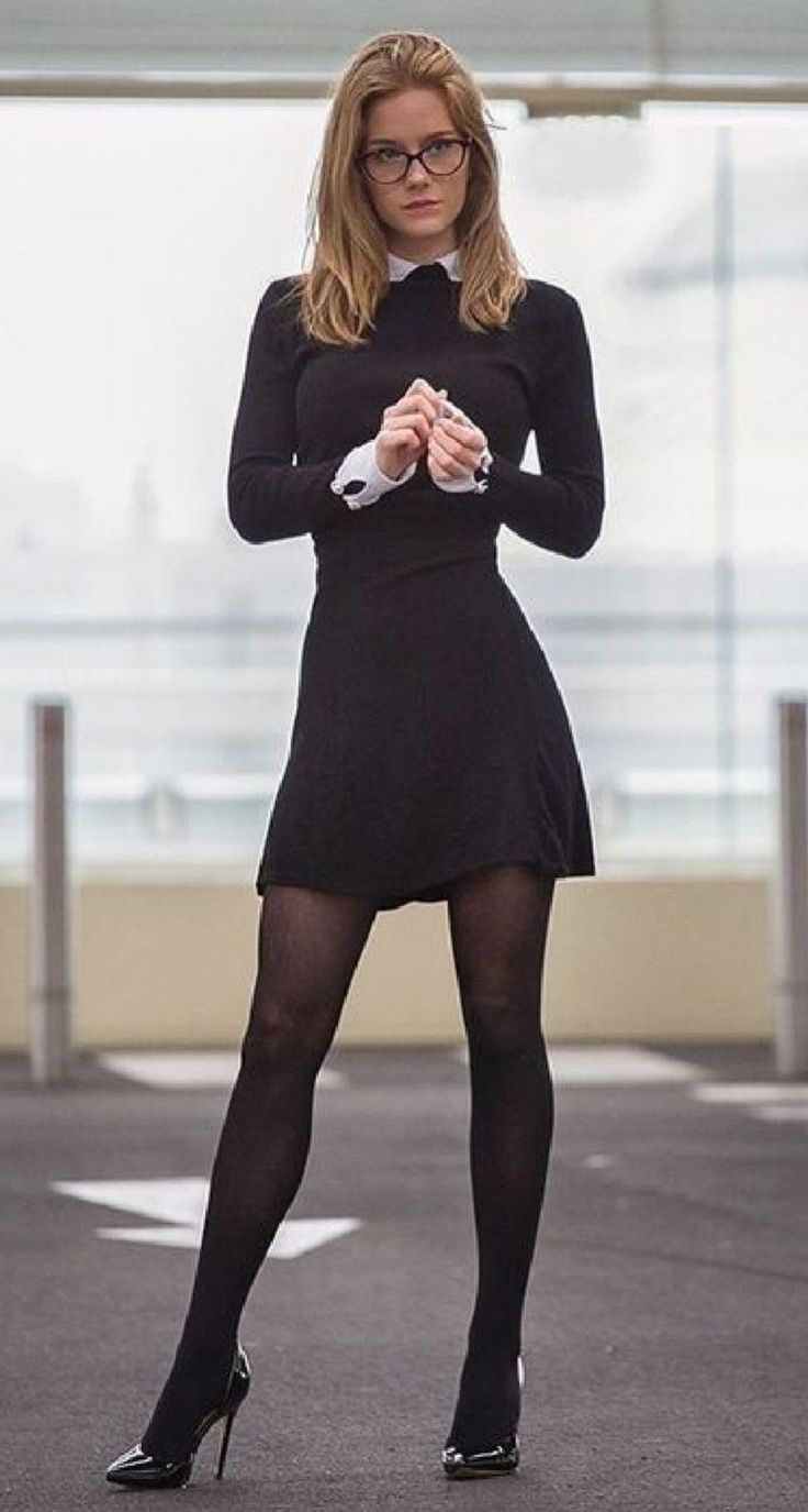 Woman in a black dress and glasses standing outdoors