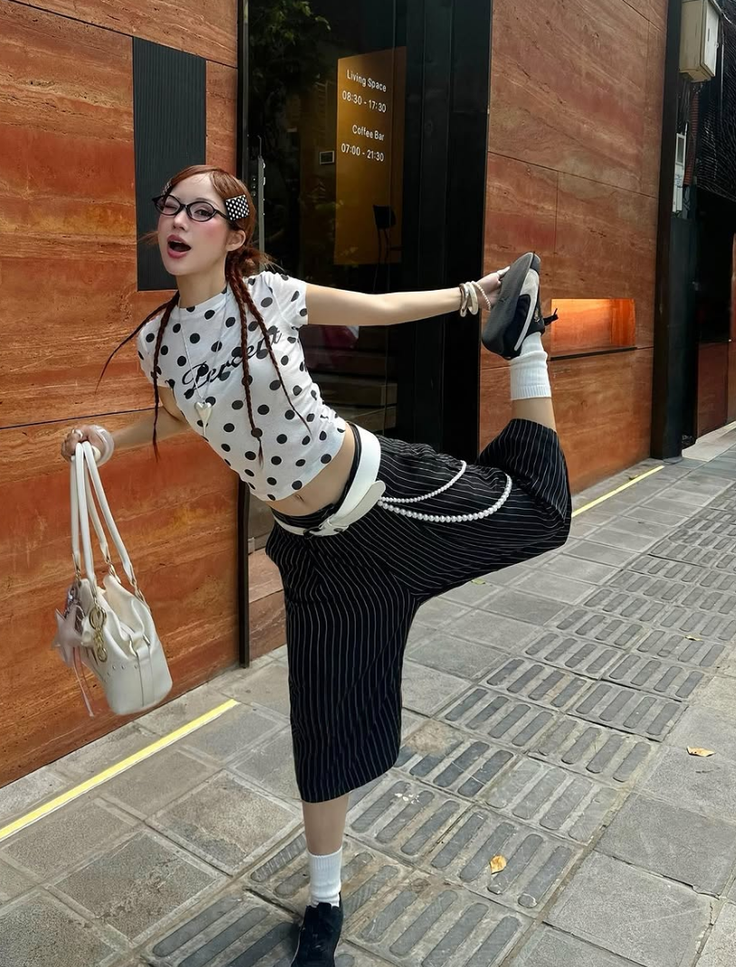 Woman in a polka dot top and pinstripe pants posing on a street
