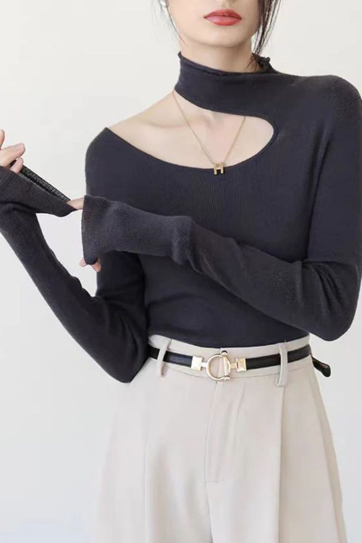 Woman wearing a black cut-out long sleeve top and light pants with a belt