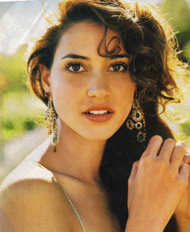 Woman with long curly hair and large earrings outdoors