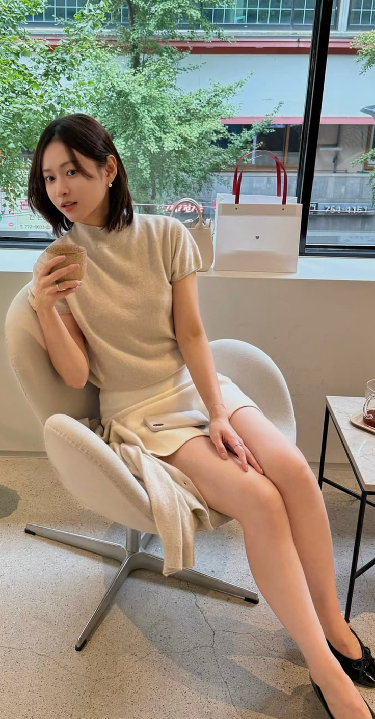 Woman with short hair sitting in a chair indoors, holding a cup
