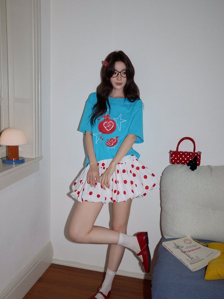 Woman in a blue t-shirt and polka dot skirt posing indoors