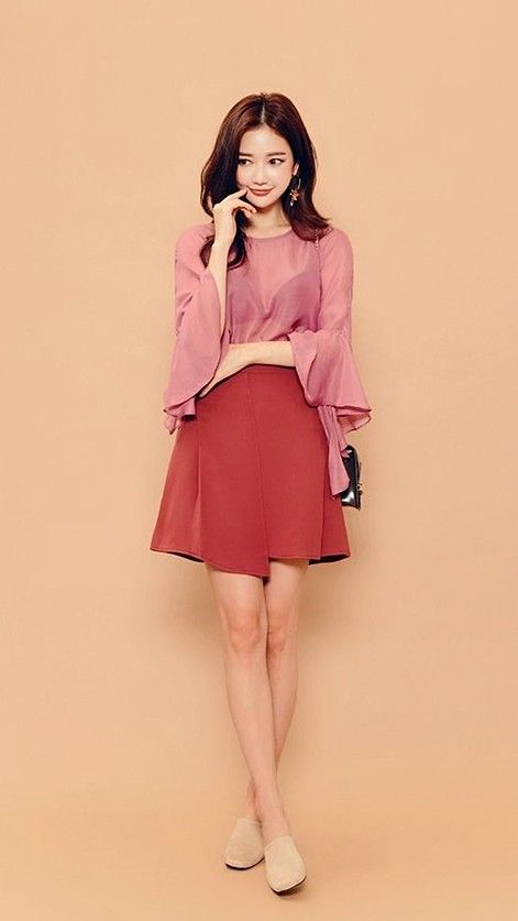 Woman in a pink blouse and red skirt posing in a studio