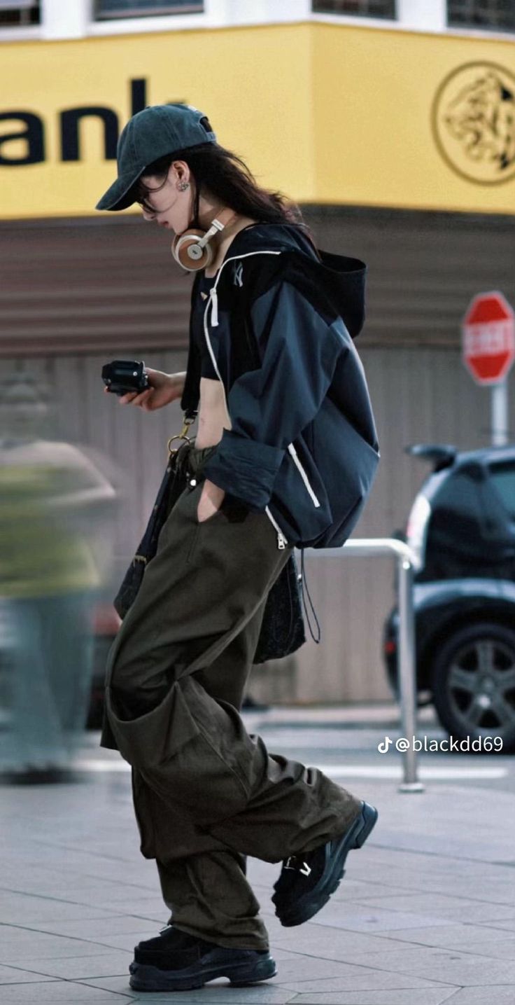 Person in streetwear with a baseball cap and headphones walking outdoors