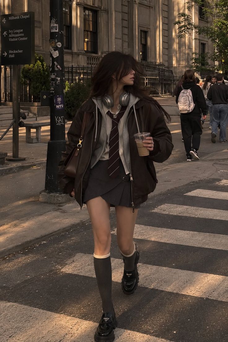 Young woman in a school uniform and brown jacket walking on a city street