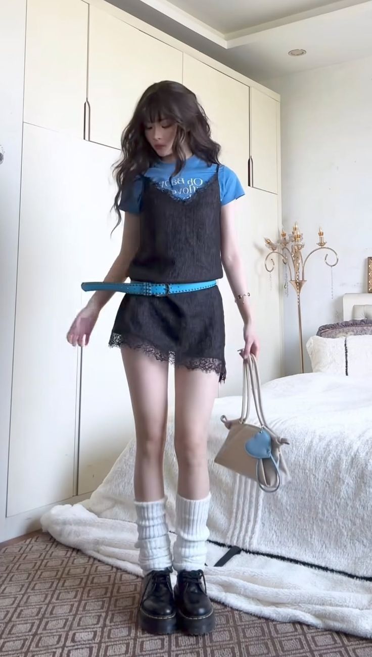 Woman in a black slip dress over a blue t-shirt with a blue belt and leg warmers